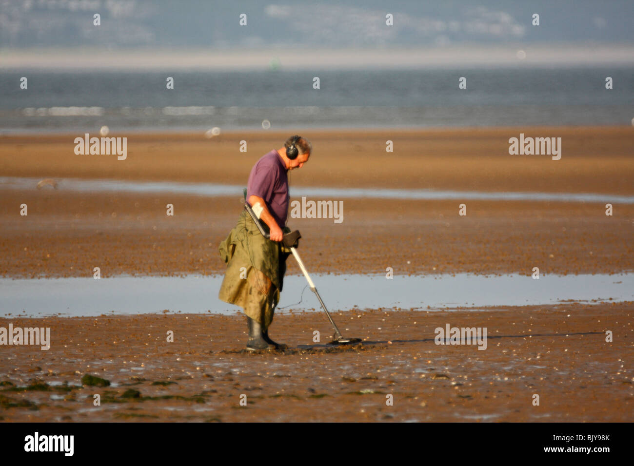 Hombre utilizando un detector de metales en una playa de arena Foto de stock