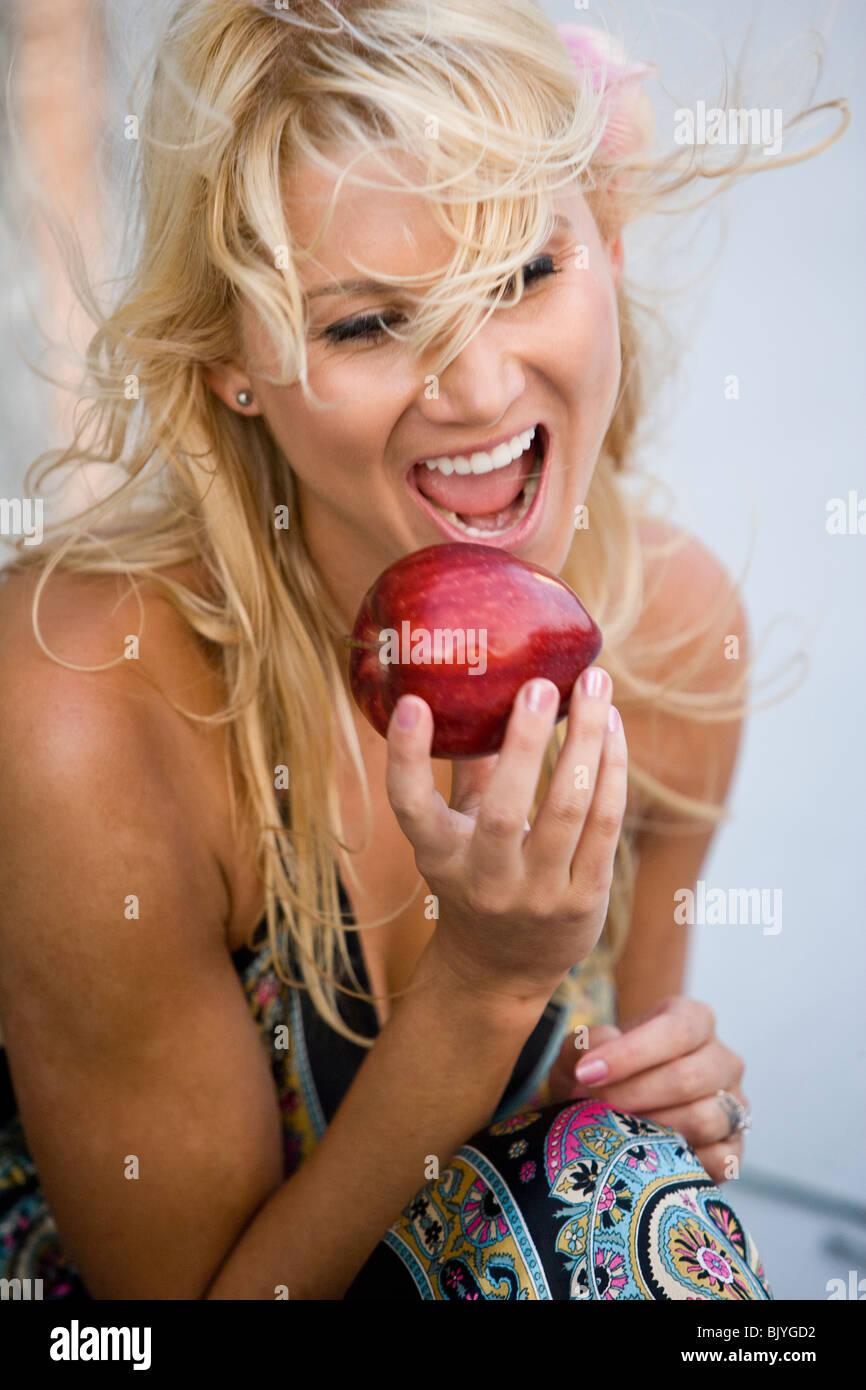 Joven Mujer rubia acerca de morder manzana roja Foto de stock