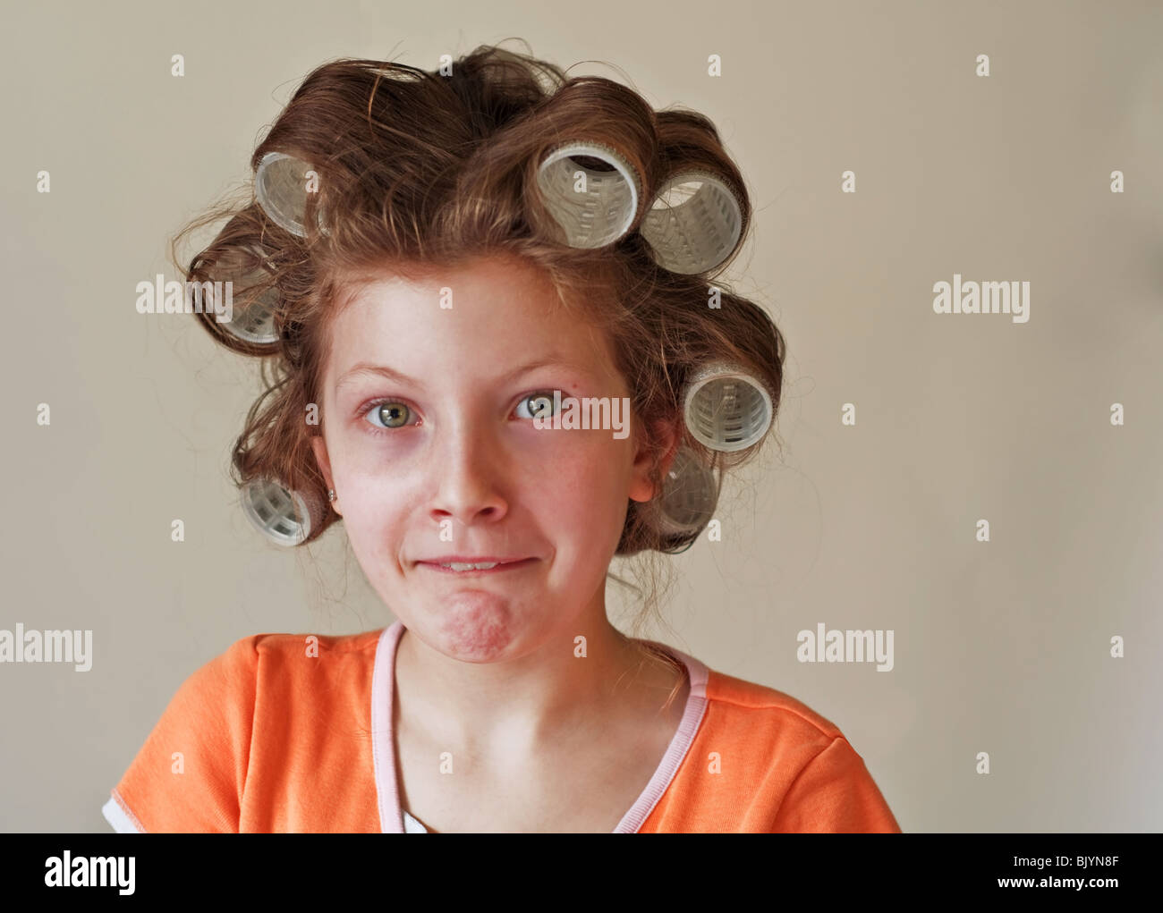 Esta imagen es una niña de 9 año de edad caucásico con ojos verdes, tiene su pelo en los rodillos (rulo) y tener un humor facial. Foto de stock