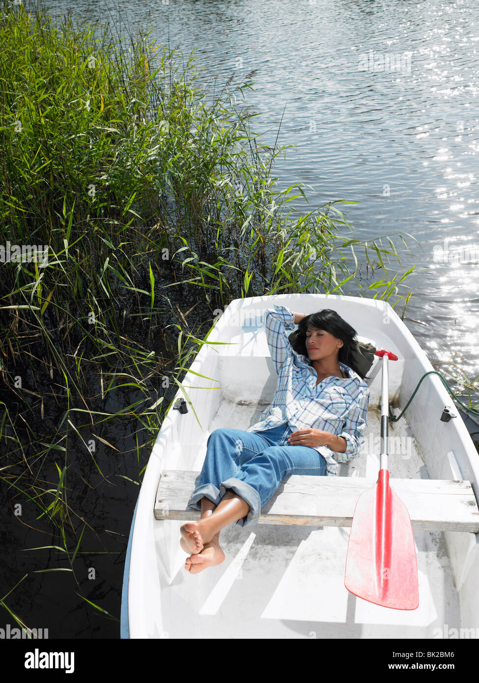 Mujer tomando una siesta en un bote de remo Foto de stock