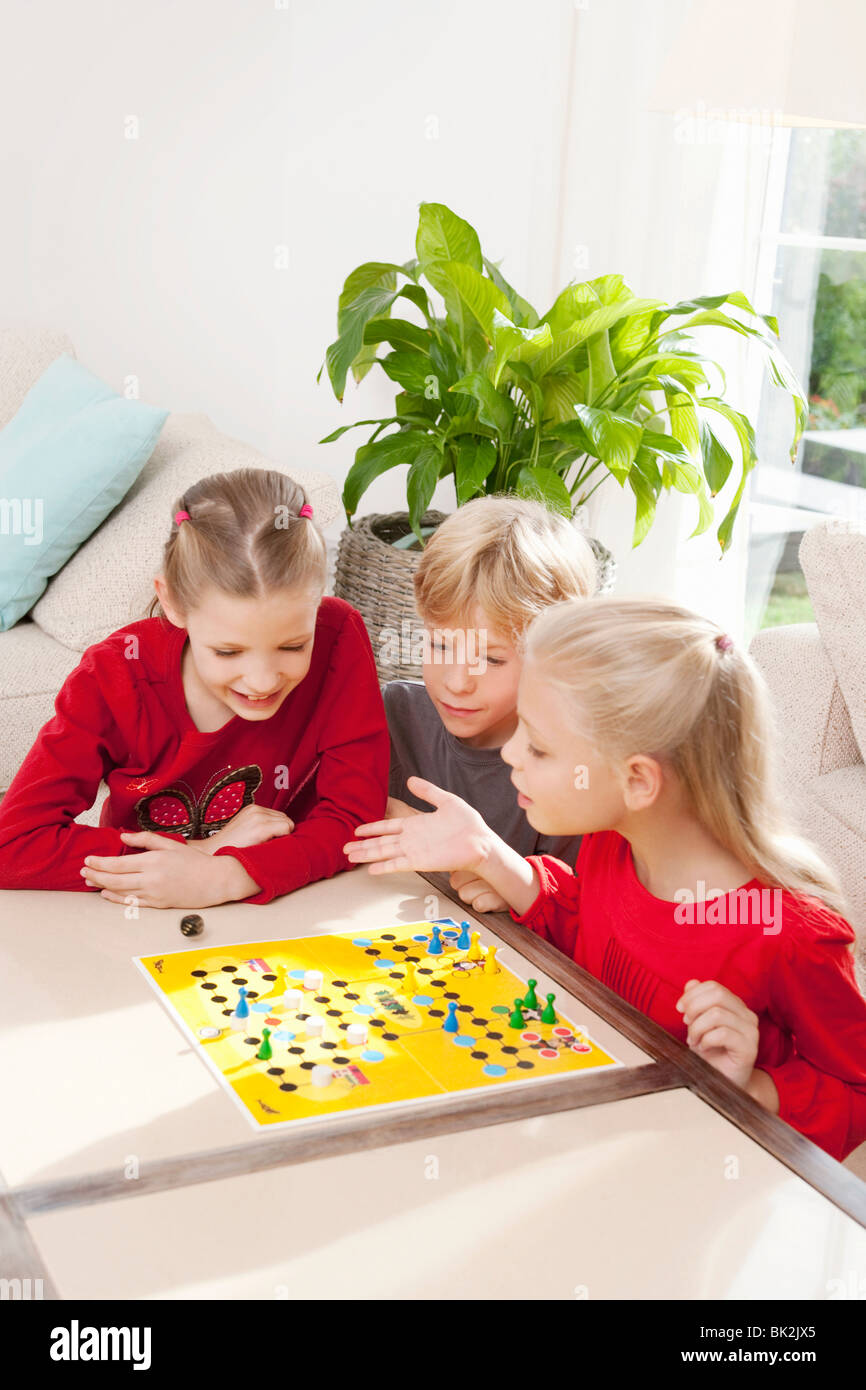 Tres niños jugando un juego de tablero Foto de stock