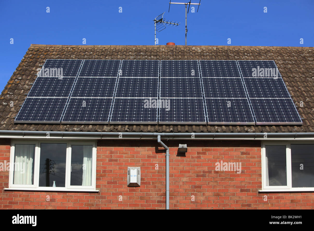 Una casa residencial en el Reino Unido con el nuevo sistema de panel solar en el techo en un soleado día de cielo azul claro Foto de stock