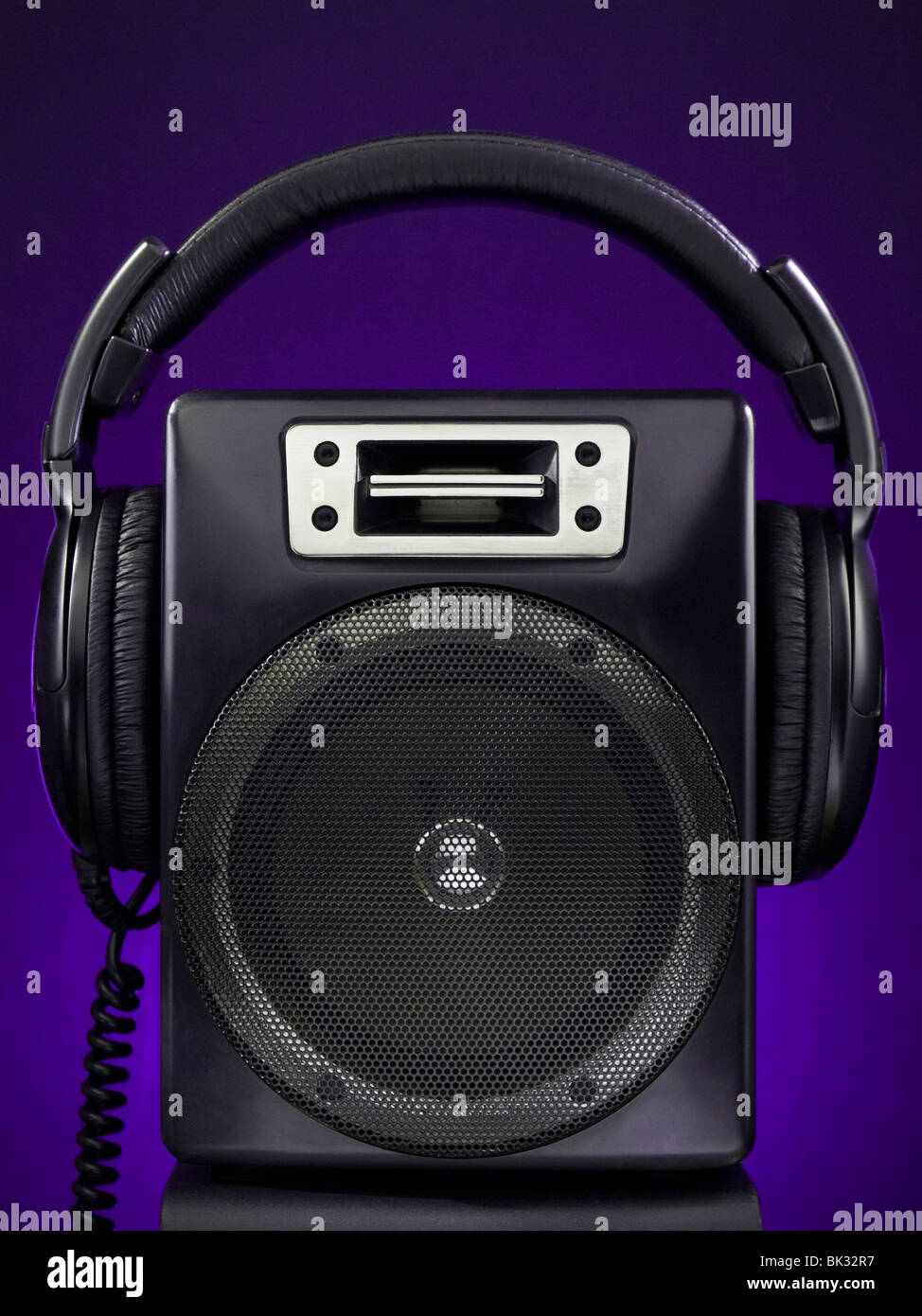Un altavoz y los auriculares sobre un fondo violeta. Foto de stock