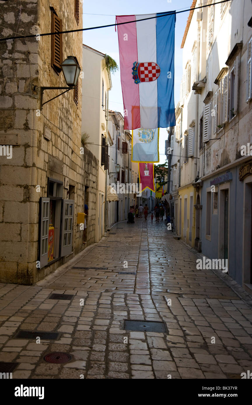 Banderas medievales y empedrado en la calle principal de compras, Srednja Street, Rab Town, isla de Rab, Kvarner, Croacia Foto de stock