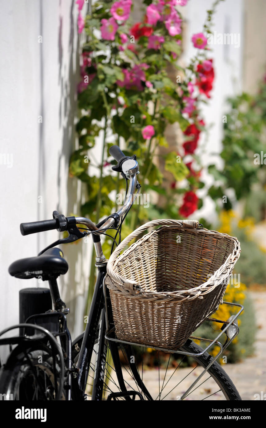 Bicicleta con canasto y hollyhocks, Ars-en-re, Ile de Re, Charente-Maritime, Francia, Europa Foto de stock