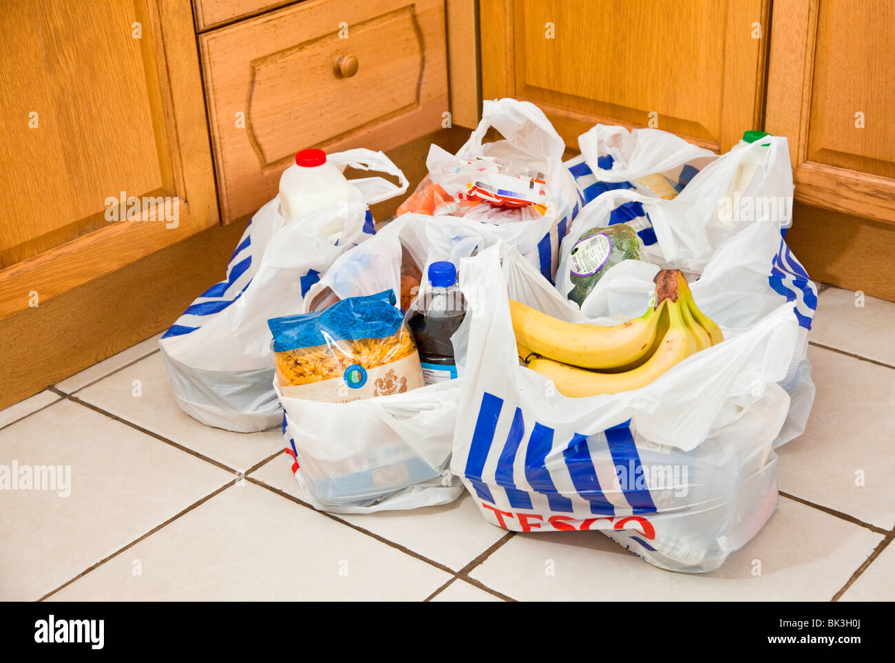 Tesco bolsas llenas de compras en un piso de la cocina UK Foto de stock