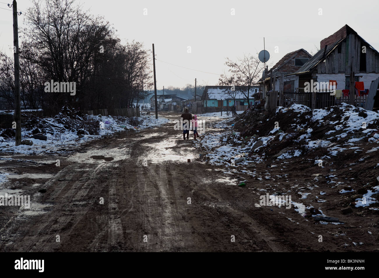 El empobrecido distrito romaní de Arad, apodado 'Apple' Street. Una familia hacen su camino a través de la nieve y barro. Foto de stock