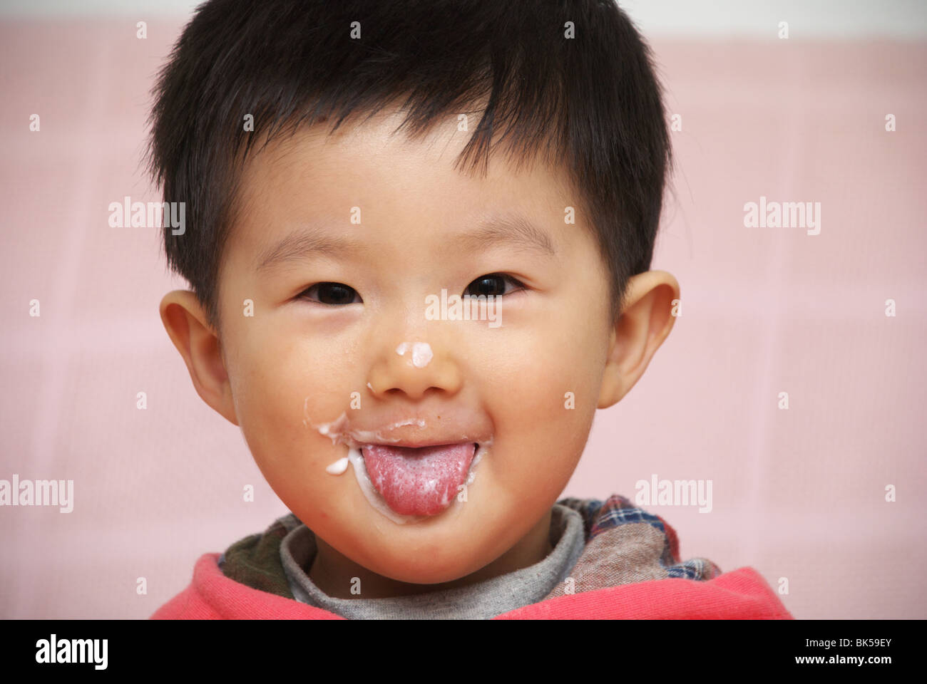 Bebé asiática con yogurt en la cara Foto de stock