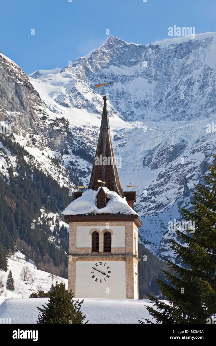 Montañas cubiertas de hielo y nieve por encima de la iglesia de la aldea de Grindelwald, la región de Jungfrau, en el Oberland bernés en Suiza Alpes Foto de stock