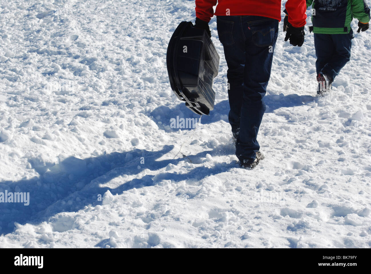 Niño de 7 lleva su trineo back up la ladera de montaña cubiertas de nieve Foto de stock