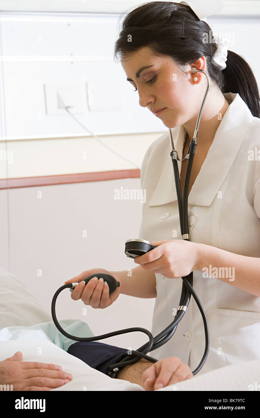 Enfermera con manómetro de presión sanguínea del paciente Foto de stock