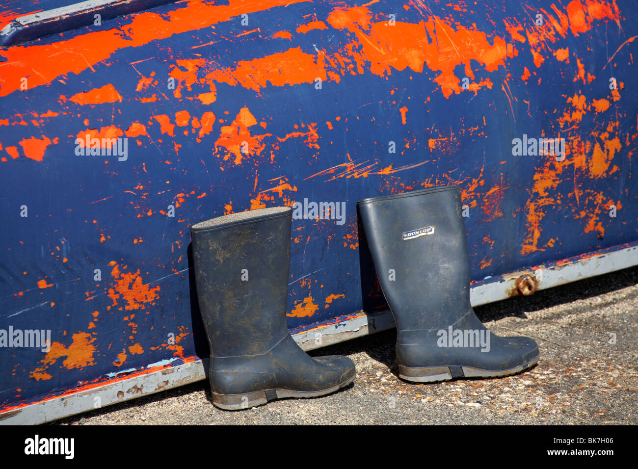 Par de botas Wellington Dunlop delante de un barco volcado con azul y  naranja pintura desconchada Fotografía de stock - Alamy