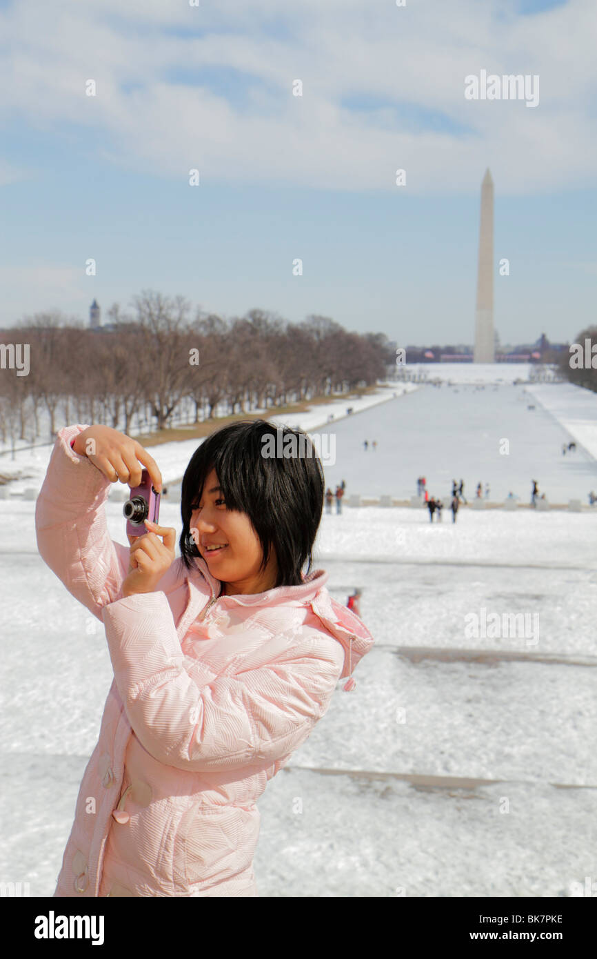 Washington DC, West Potomac Park, National Mall & Memorial Parks, The Reflecting Pool, vista del Monumento a Washington, historia, hielo, nieve, chica asiática Foto de stock