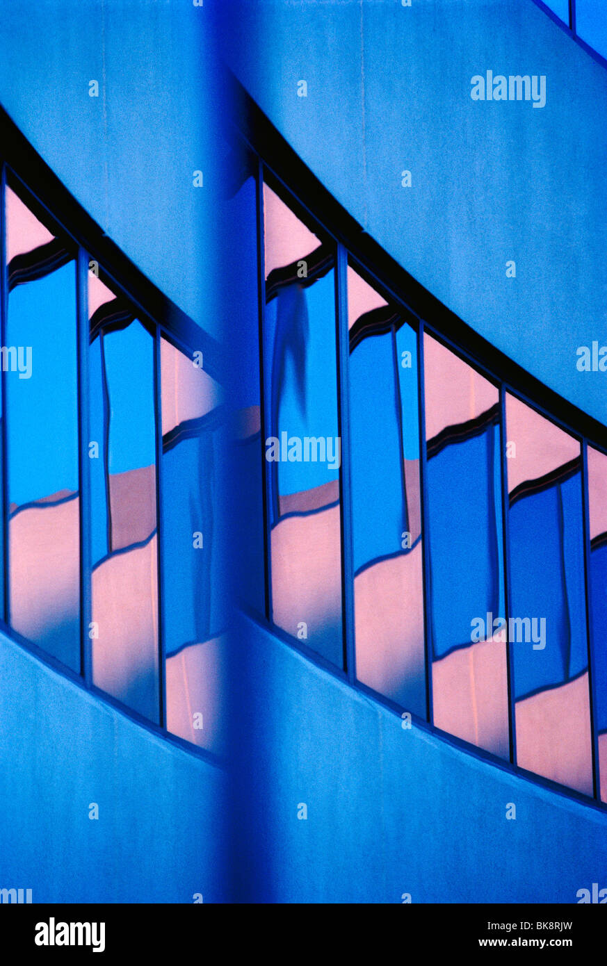 Visión abstracta de un moderno edificio de oficinas corporativas incluyen reflexiones en las ventanas de el cielo del atardecer Foto de stock
