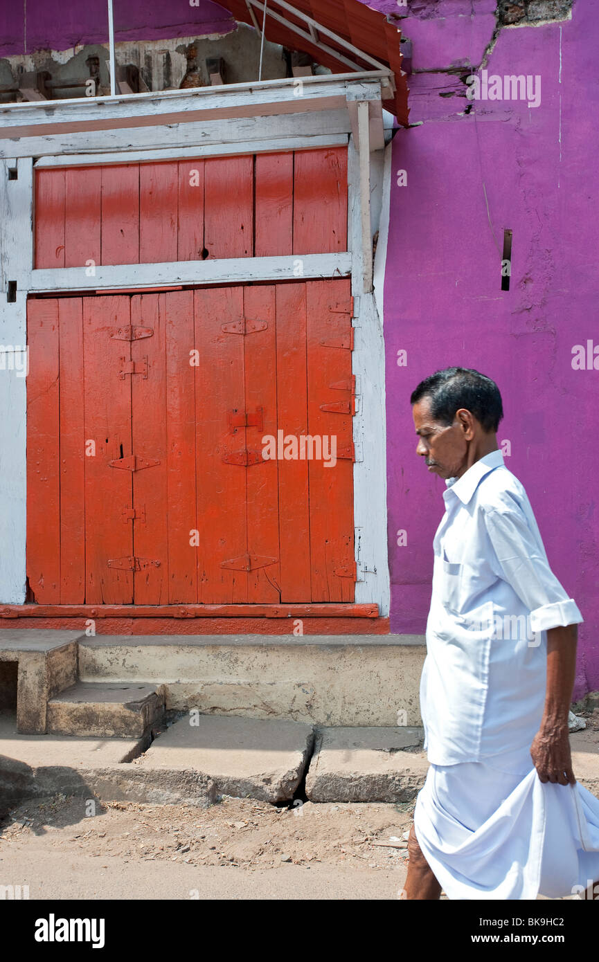 Hombre caminando local pasado almacén almacén cerca de la orilla, Fort Cochin, Kerala, India Foto de stock