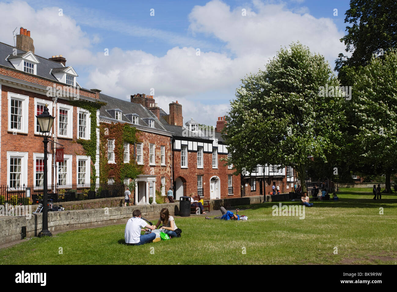 La gente relajándose en gras en catedral cerca, Exeter, Devon, Inglaterra, Reino Unido Foto de stock