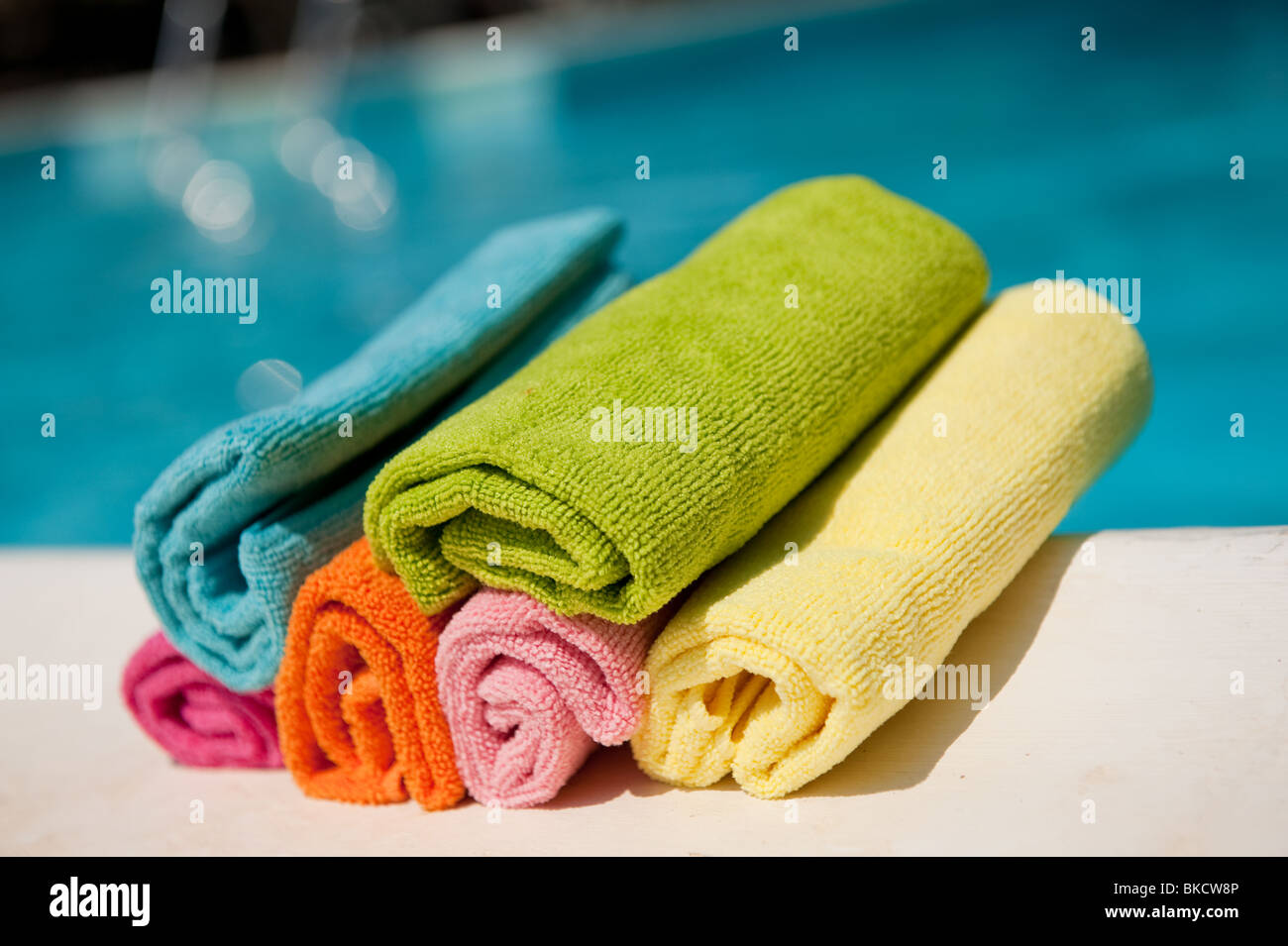 Coloridas toallas enrolladas, cerca de la piscina Foto de stock
