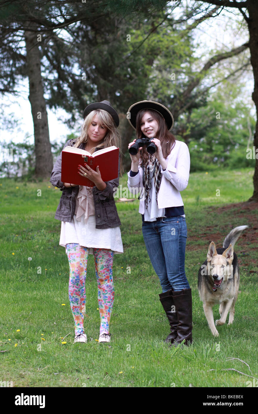 Dos adolescentes de moda avistaje de aves con guía y binoculares Foto de stock