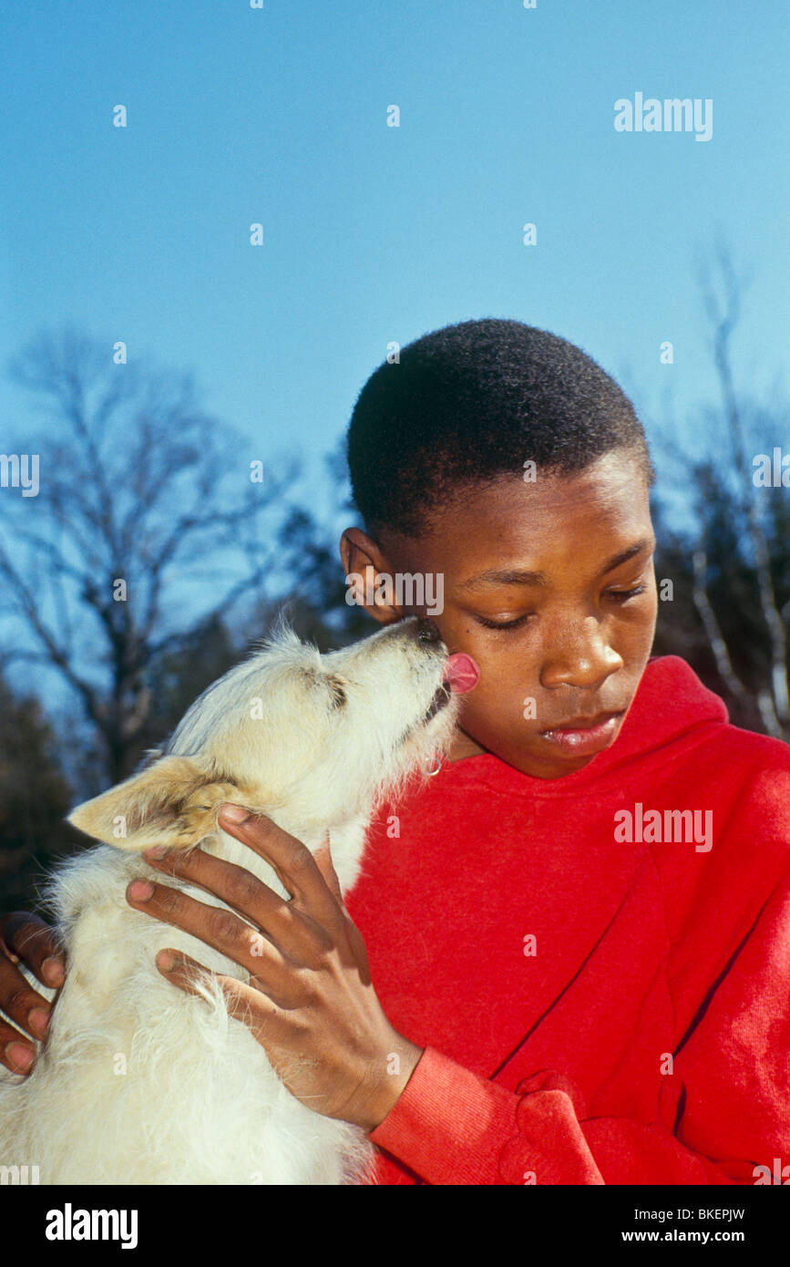 Boy saludado por su perro feliz con una manita en la cara Foto de stock