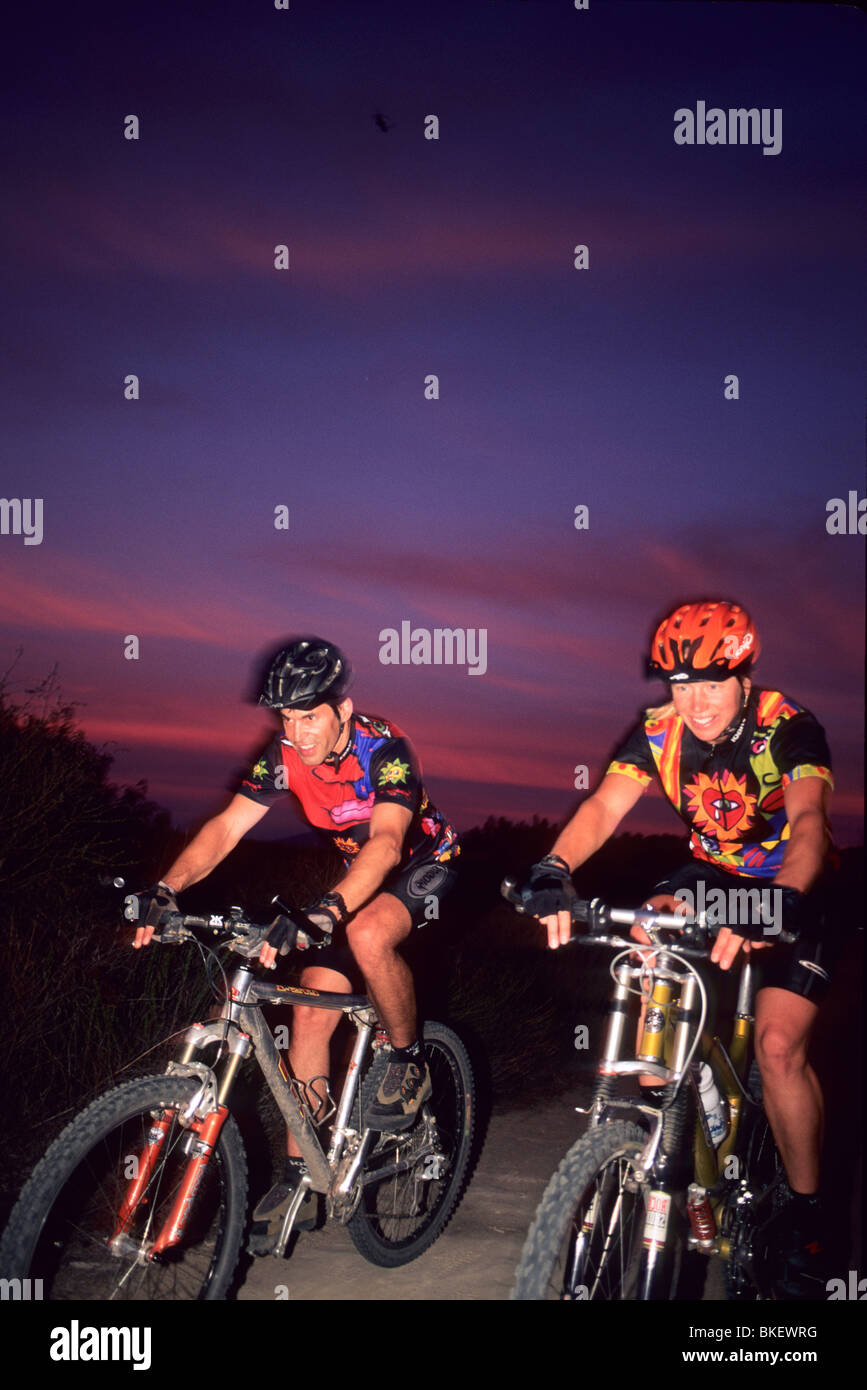 Hombre y mujer andando en bicicleta al atardecer. Foto de stock