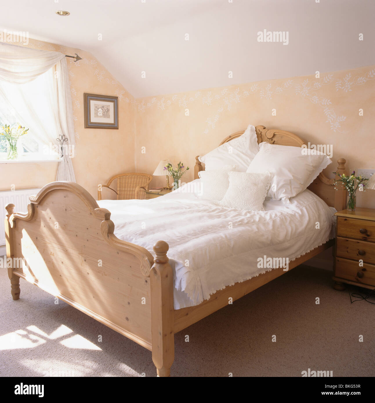 Ropa blanca de cama matrimonial en el dormitorio de pino con estarcida  flores en la pared Fotografía de stock - Alamy