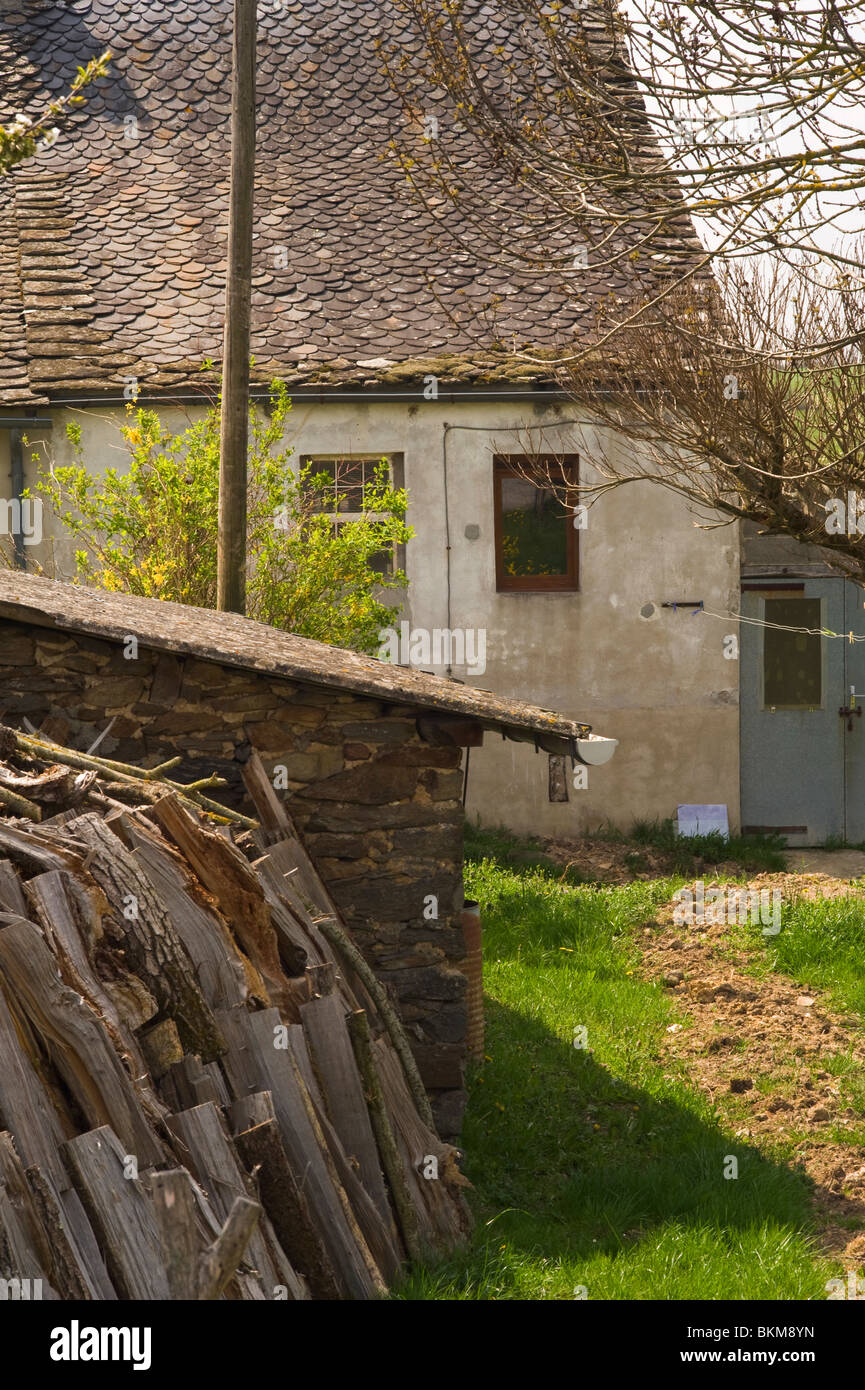 Casita rural de arquitectura tradicional francesa con garage y el montón de madera en Laval, cerca de Pradinas Francia Aveyron Foto de stock
