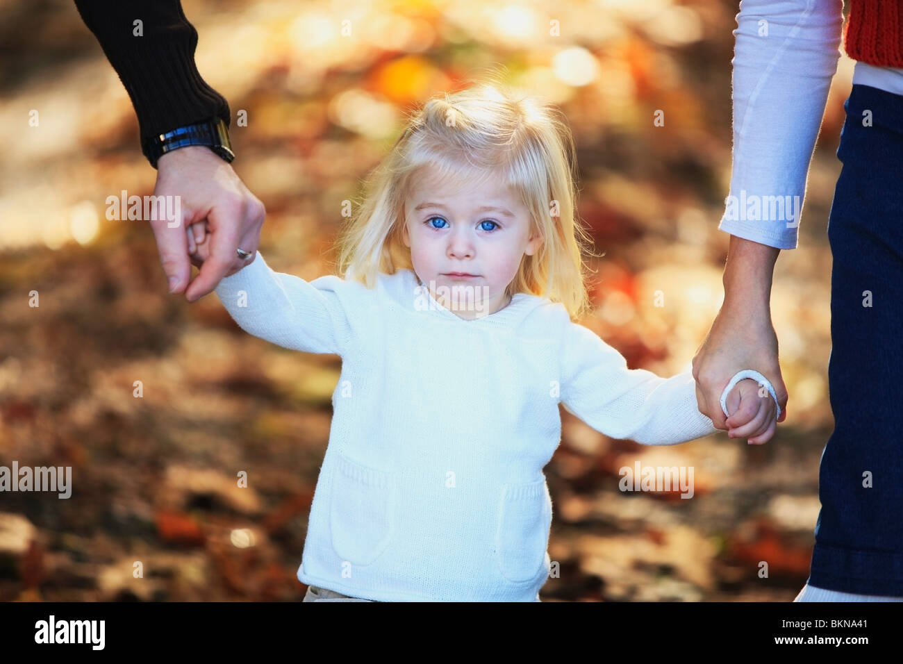 Una joven Chica sujetando las manos de sus padres Foto de stock
