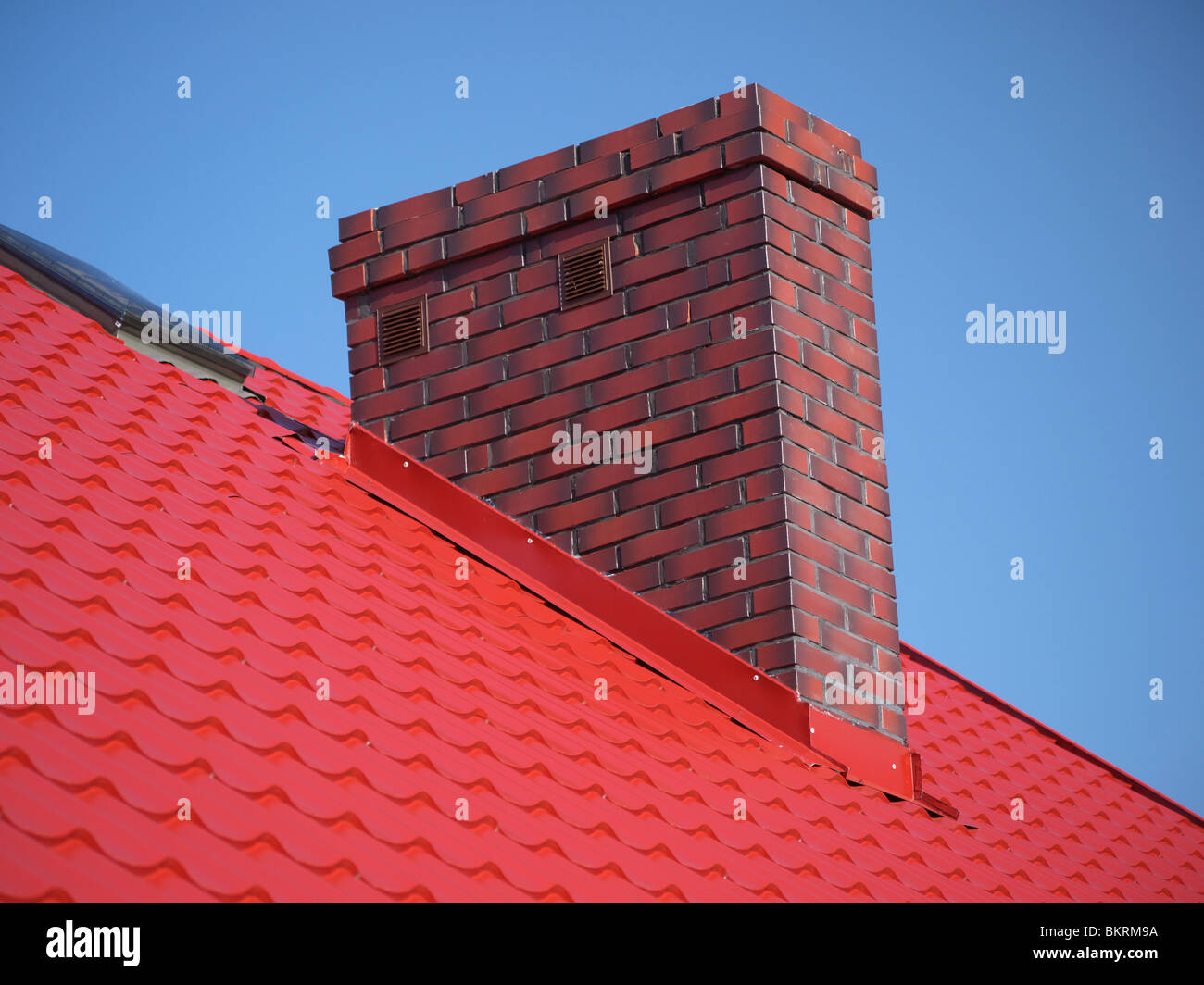 Primer plano de techo rojo metal cubriendo con chimenea de ladrillo Foto de stock