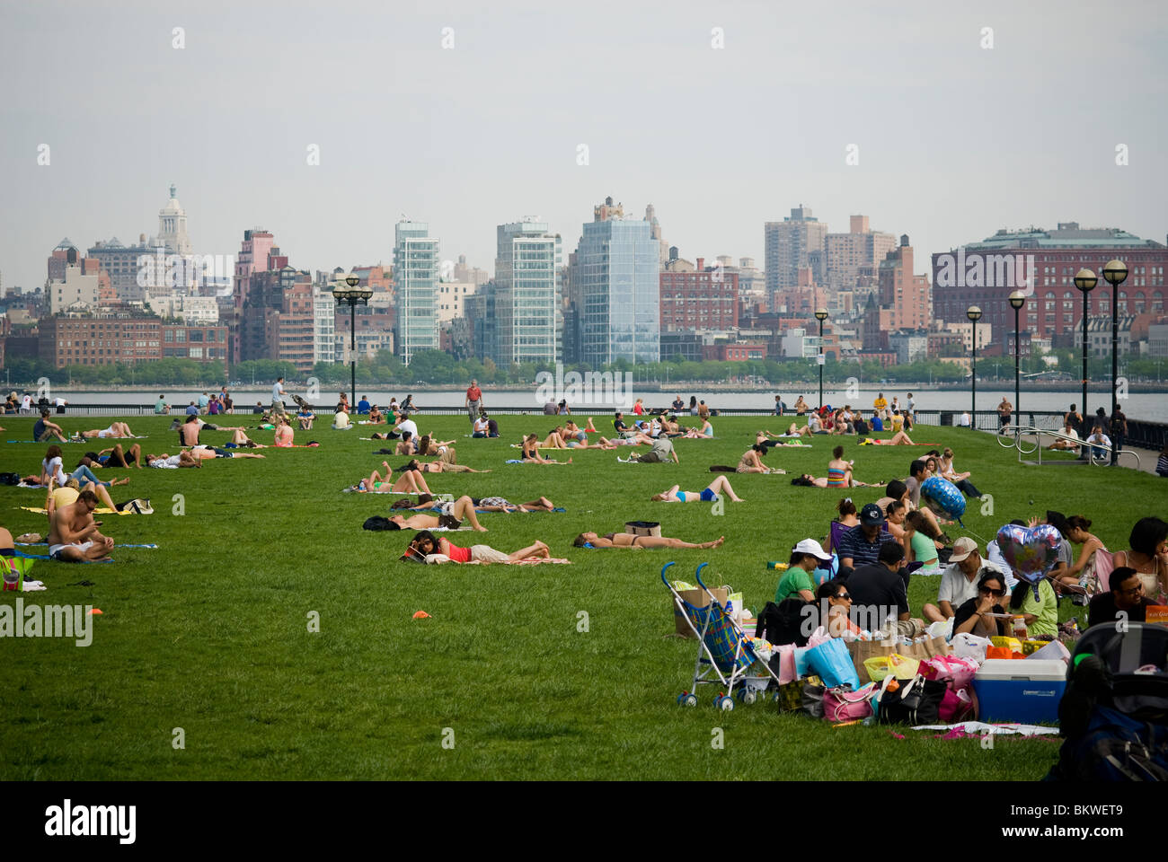 La gente aprovecha el clima cálido en el césped de un muelle en Hoboken