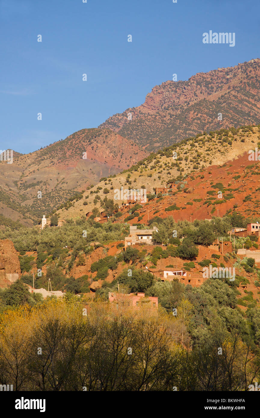 Rojo bereber amurallada aldea en las montañas Atlas colinas cerca de Setti Fatma con un minarete de la mezquita Foto de stock