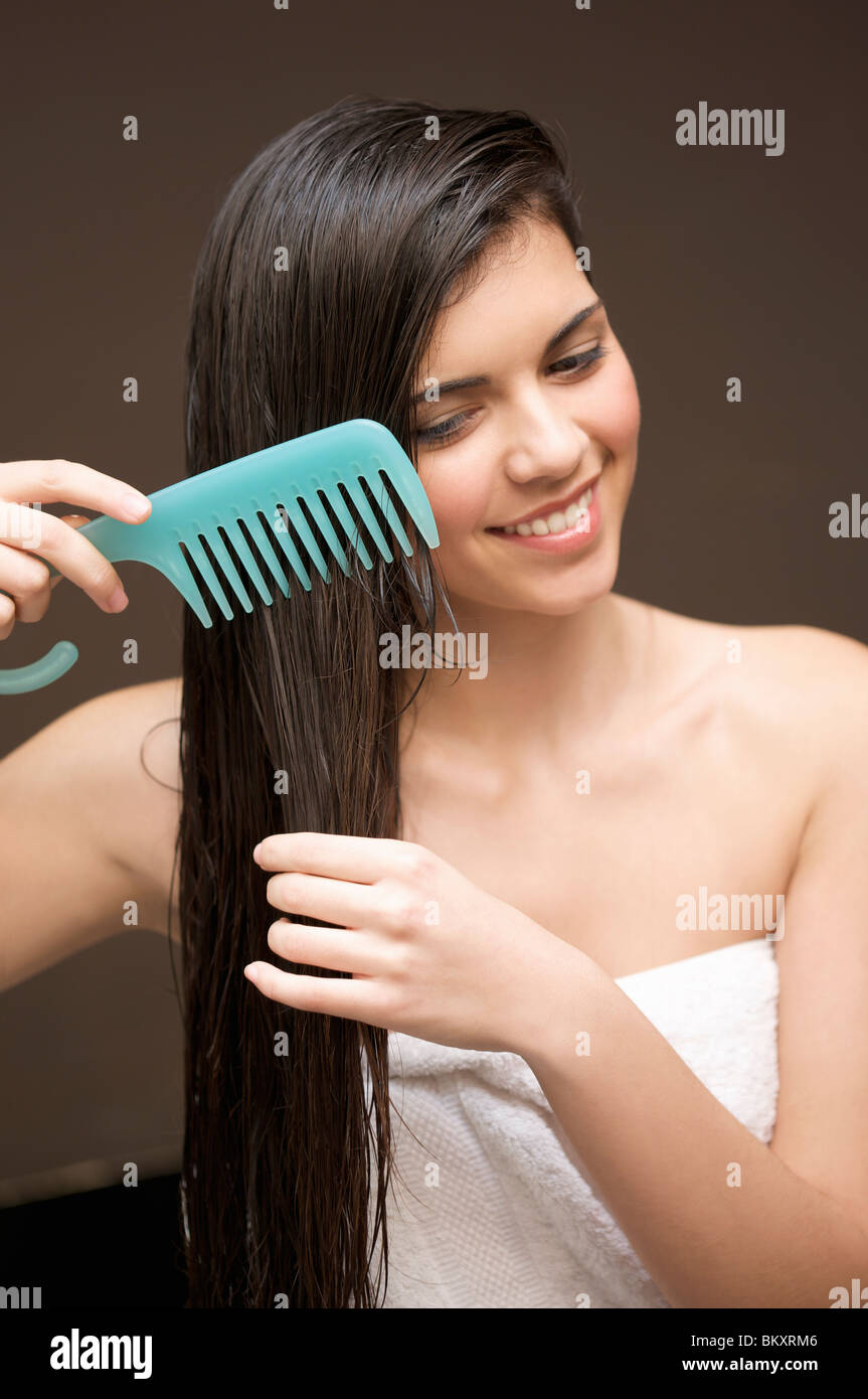 Cerca de una mujer sonriente peinar su cabello con un peine de dientes  ancho Fotografía de stock  Alamy