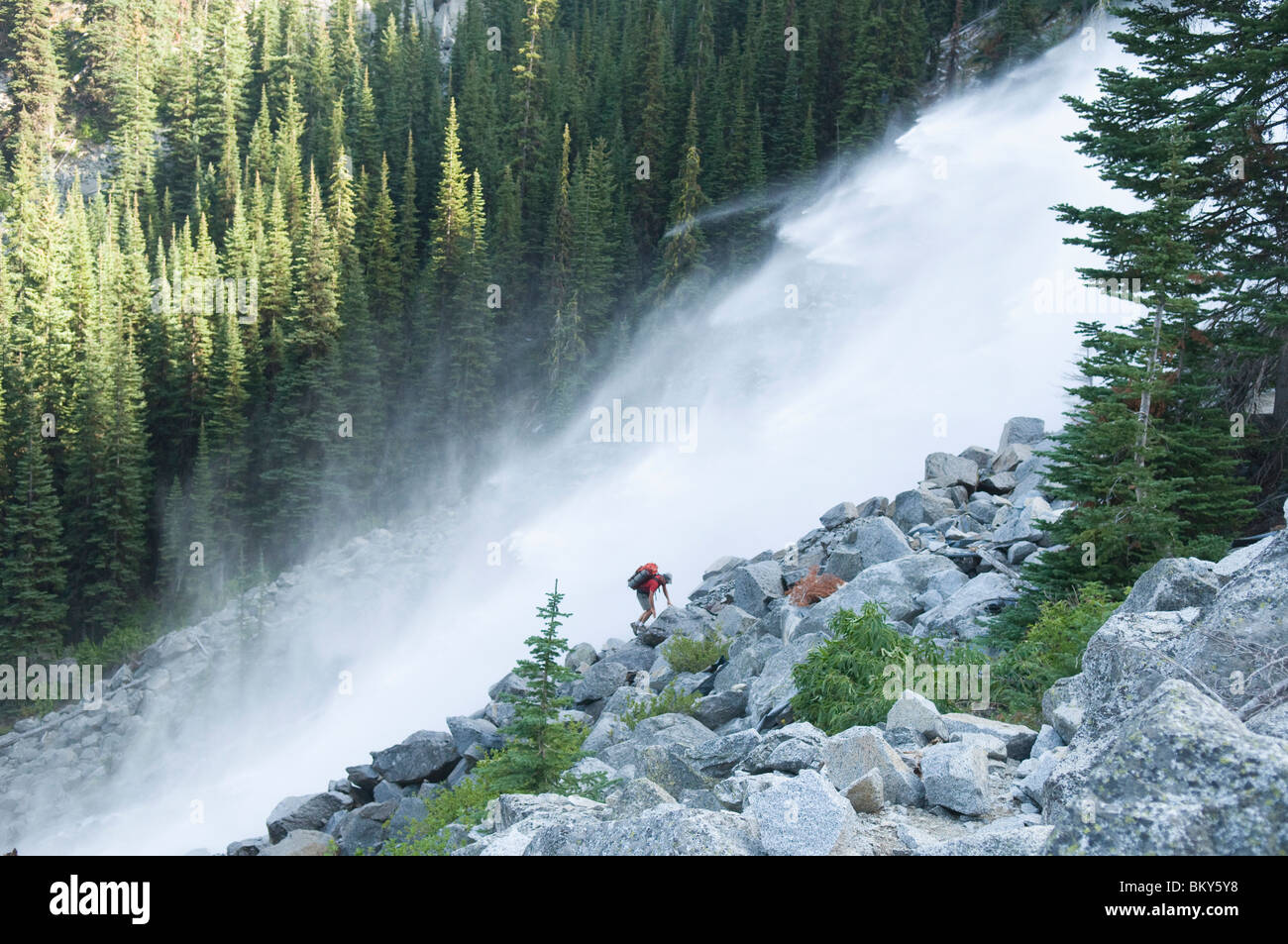 Un hombre caminatas junto a la cascada, encanto picos, lagos alpinos Desierto, Leavenworth, Washington. Foto de stock