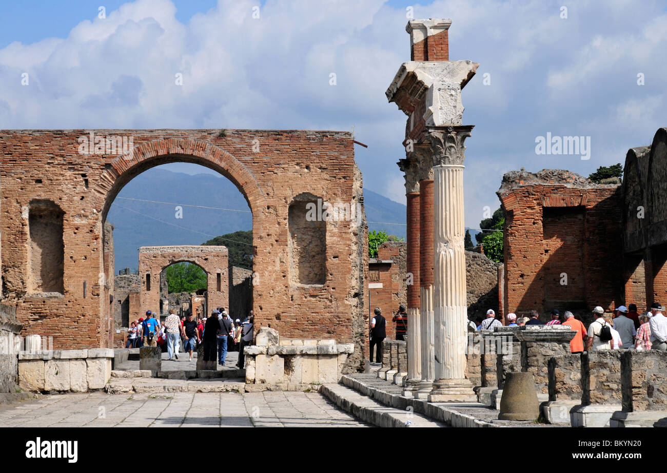 Los turistas que caminan a través del arco triunfal imperial junto a las provisiones de alimentos del mercado (macellum) en Pompeya Italia Foto de stock