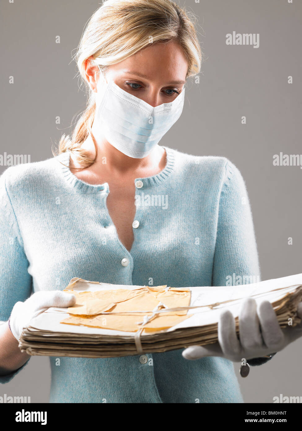 Mujer con máscara, sosteniendo sus archivos más preciados Foto de stock
