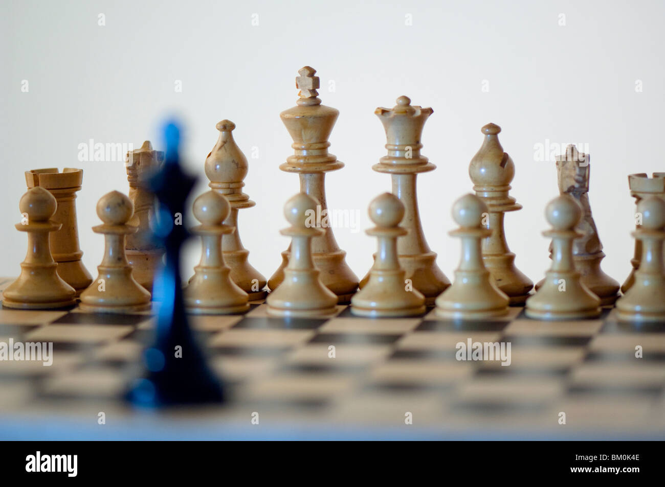 Ajedrez, rey negro en blanco delante de piezas de ajedrez en el tablero de ajedrez Foto de stock