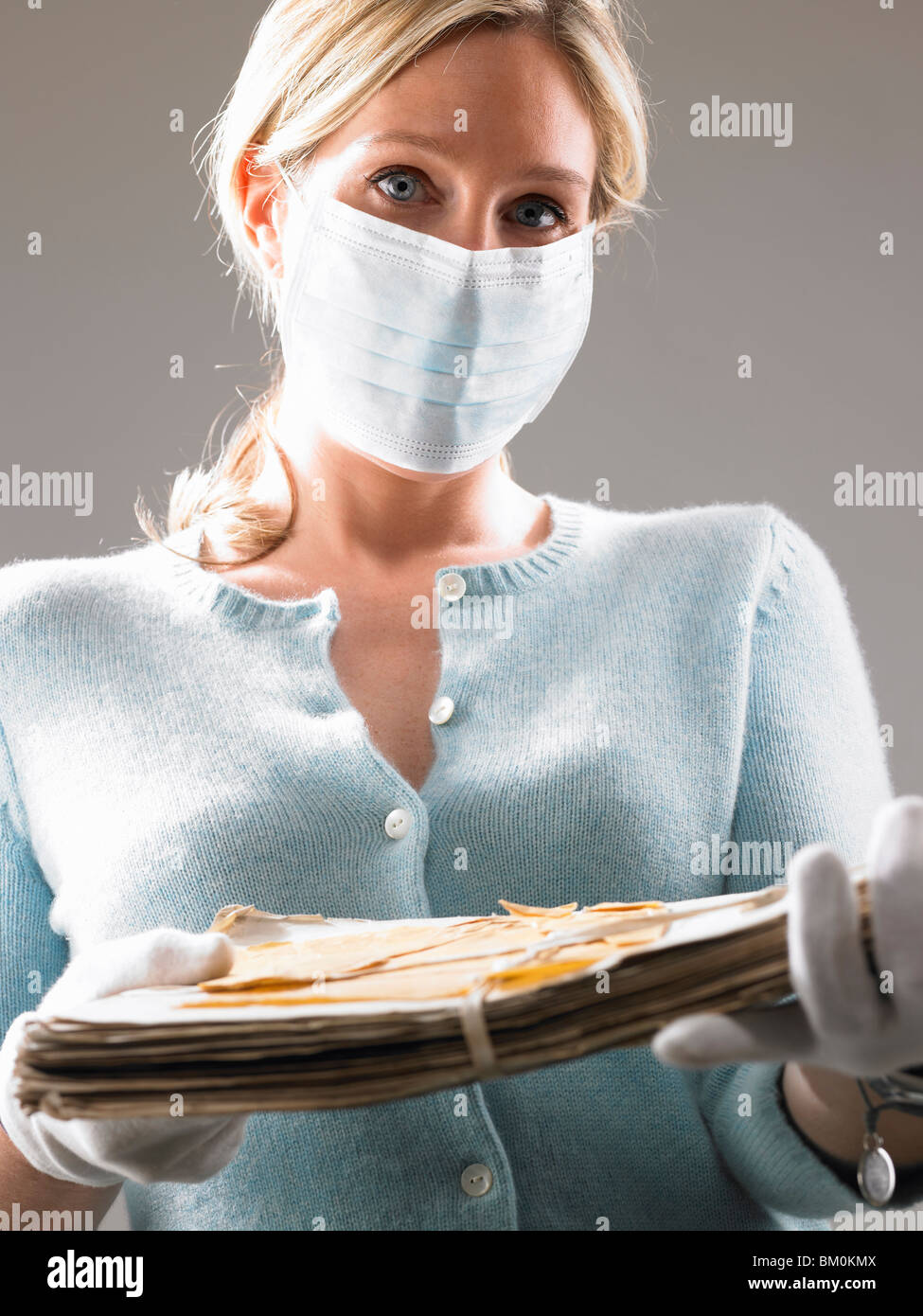 Mujer con máscara, sosteniendo sus archivos más preciados Foto de stock