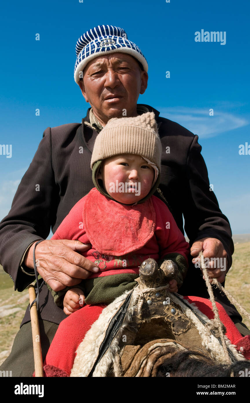 El abuelo con su nieto a caballo, Song Kul, en Kirguistán Foto de stock