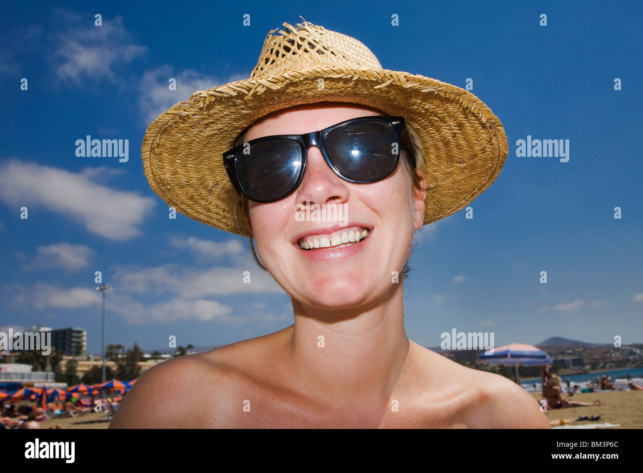 Mujer sonriente en la playa en un sombrero streaw Foto de stock
