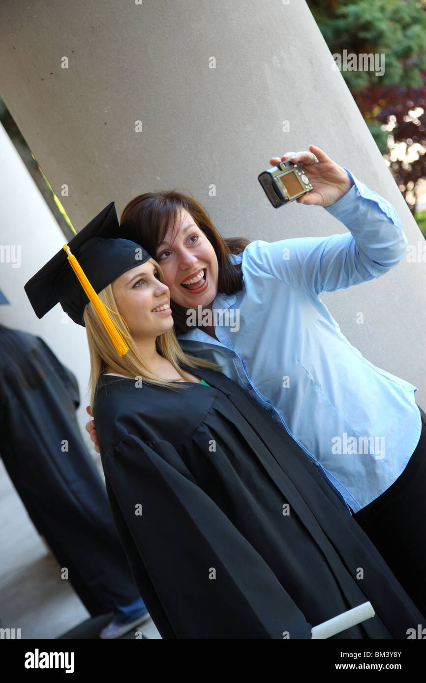 Graduados y mamá tomando foto juntos Foto de stock