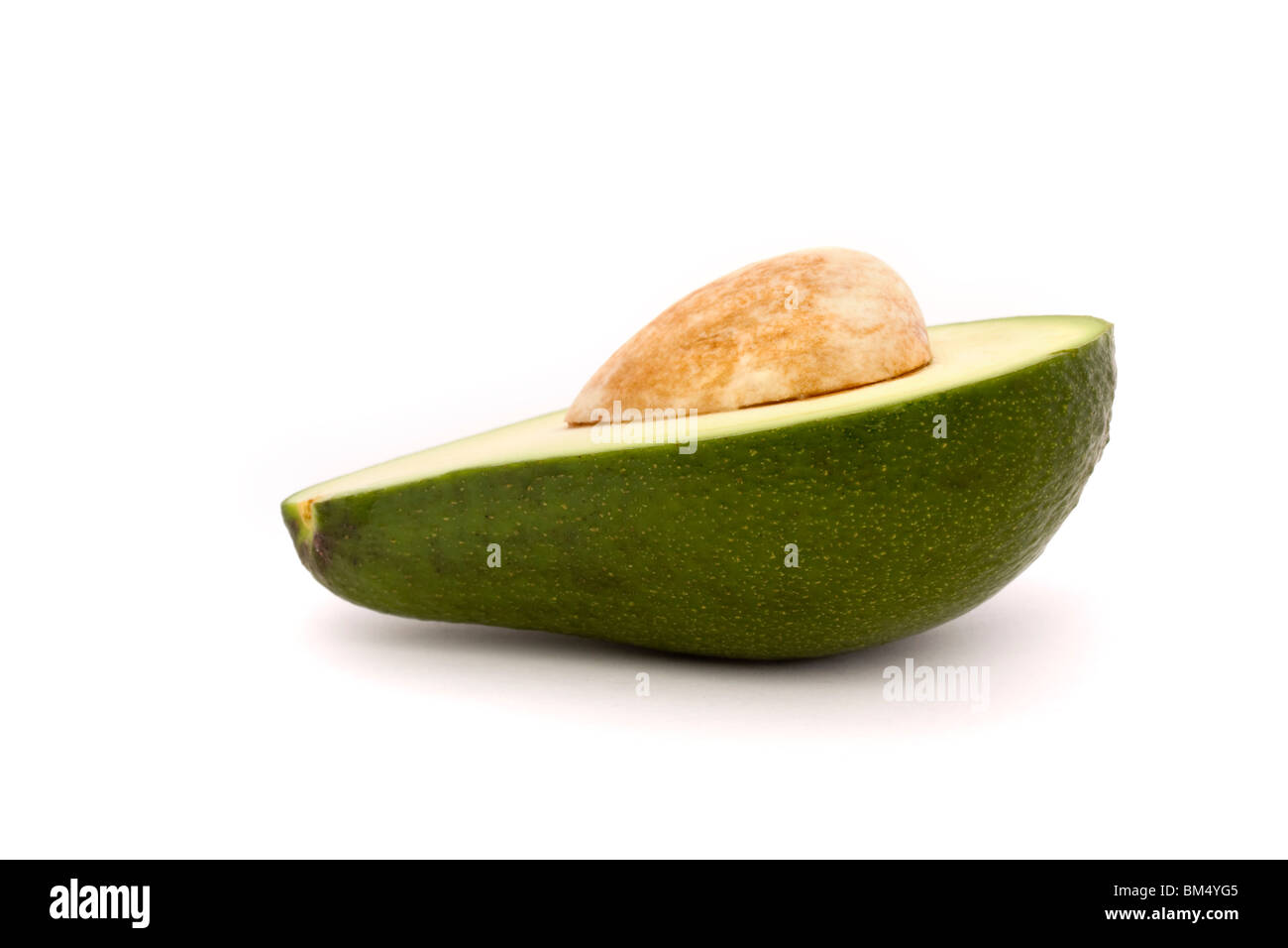 La mitad de un aguacate con piedra aislado sobre un fondo blanco. Foto de stock