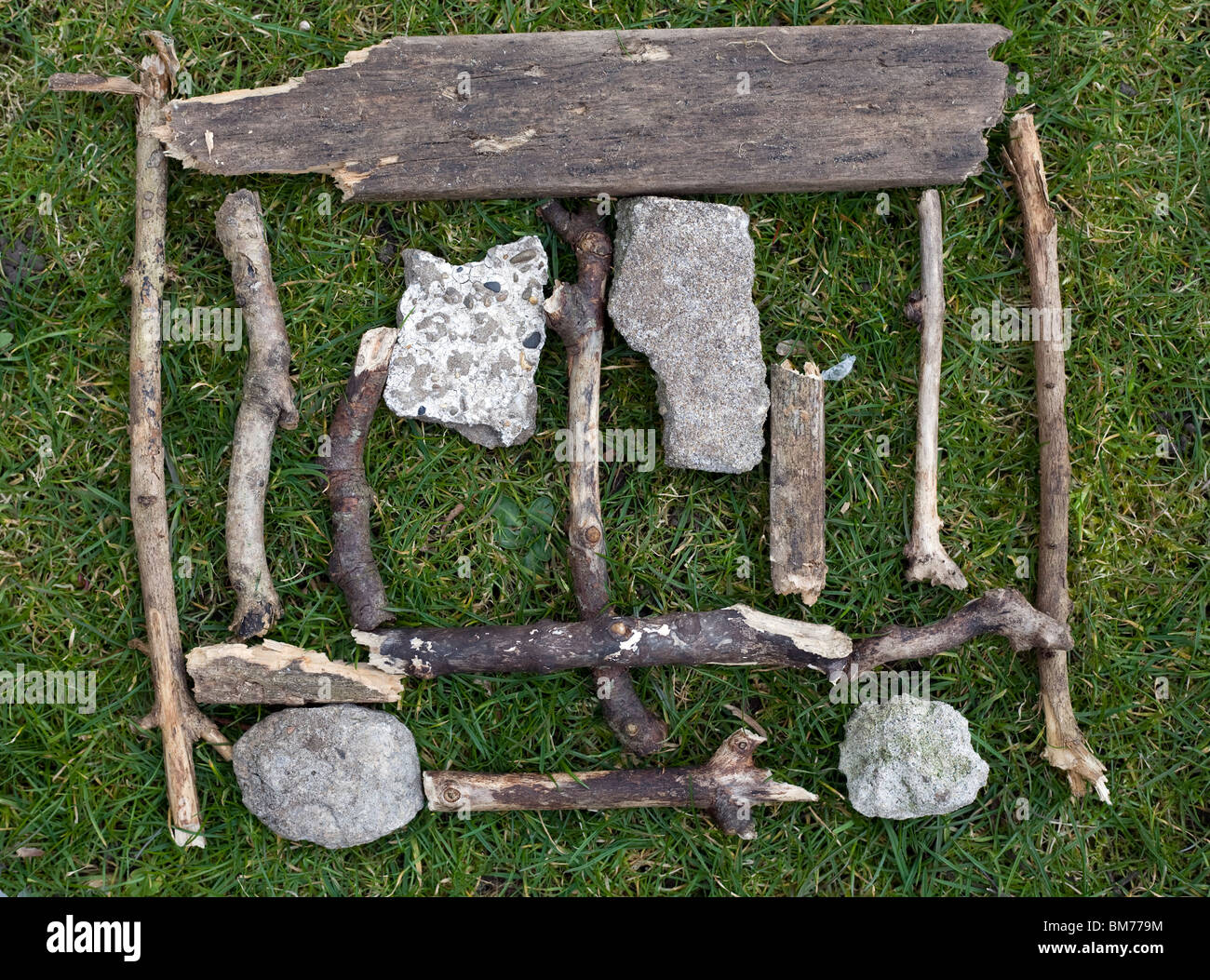 Un proyecto de arte ambiental deberes compuesto de palos y piedras sobre un fondo de hierba Foto de stock