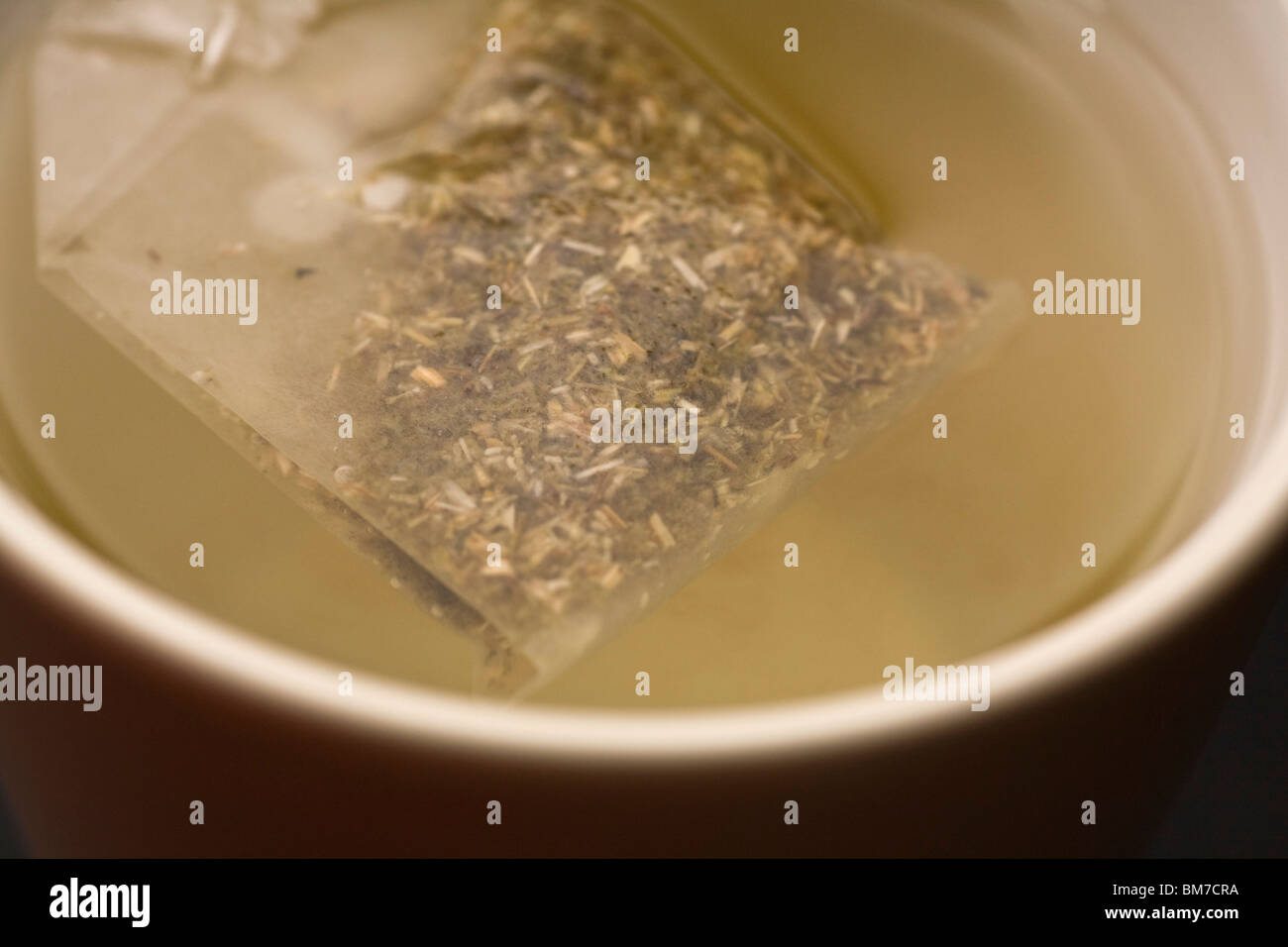 Detalle de una bolsita de té en una taza de agua Foto de stock