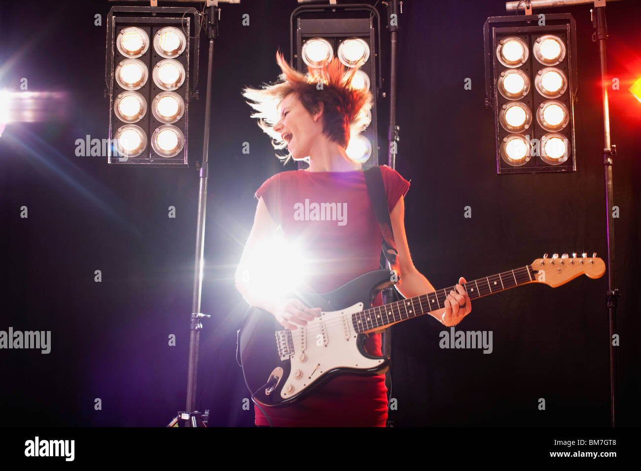 Una mujer tocando la guitarra eléctrica en el escenario realizando Foto de stock