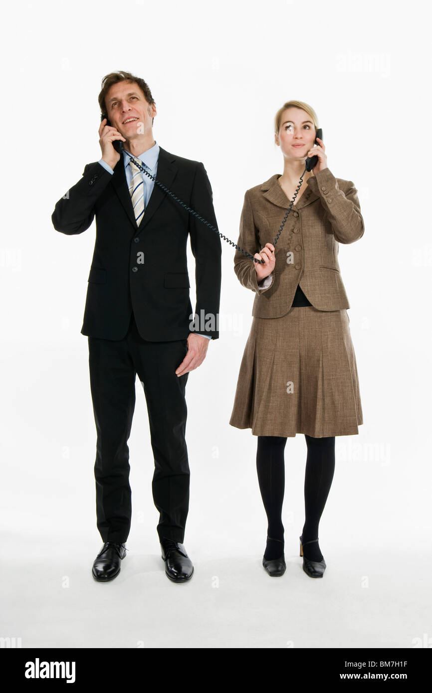 Dos personas de negocios utilizando receptores de teléfono conectado con el mismo cordón Foto de stock