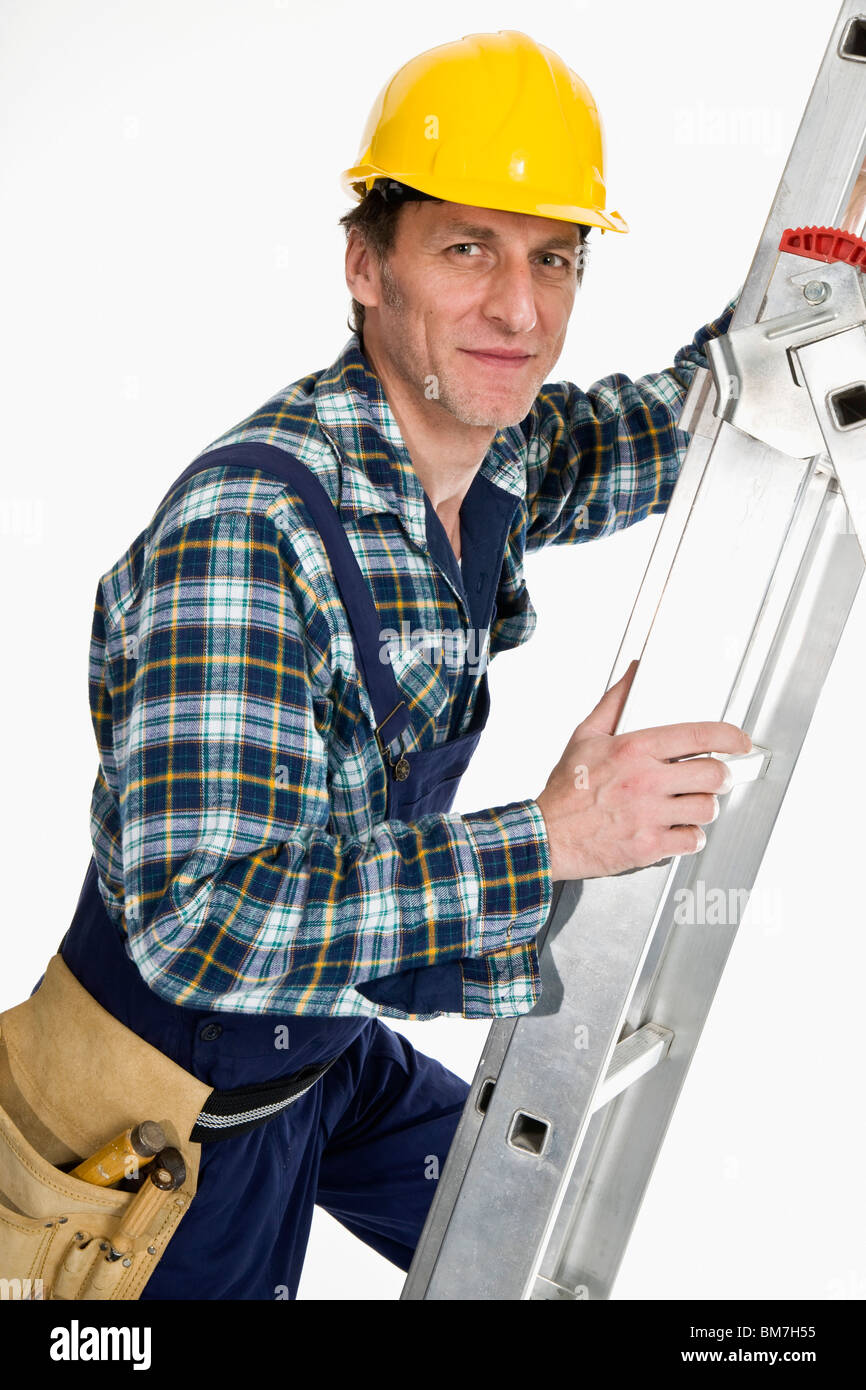 Un trabajador de la construcción subiendo una escalera Foto de stock