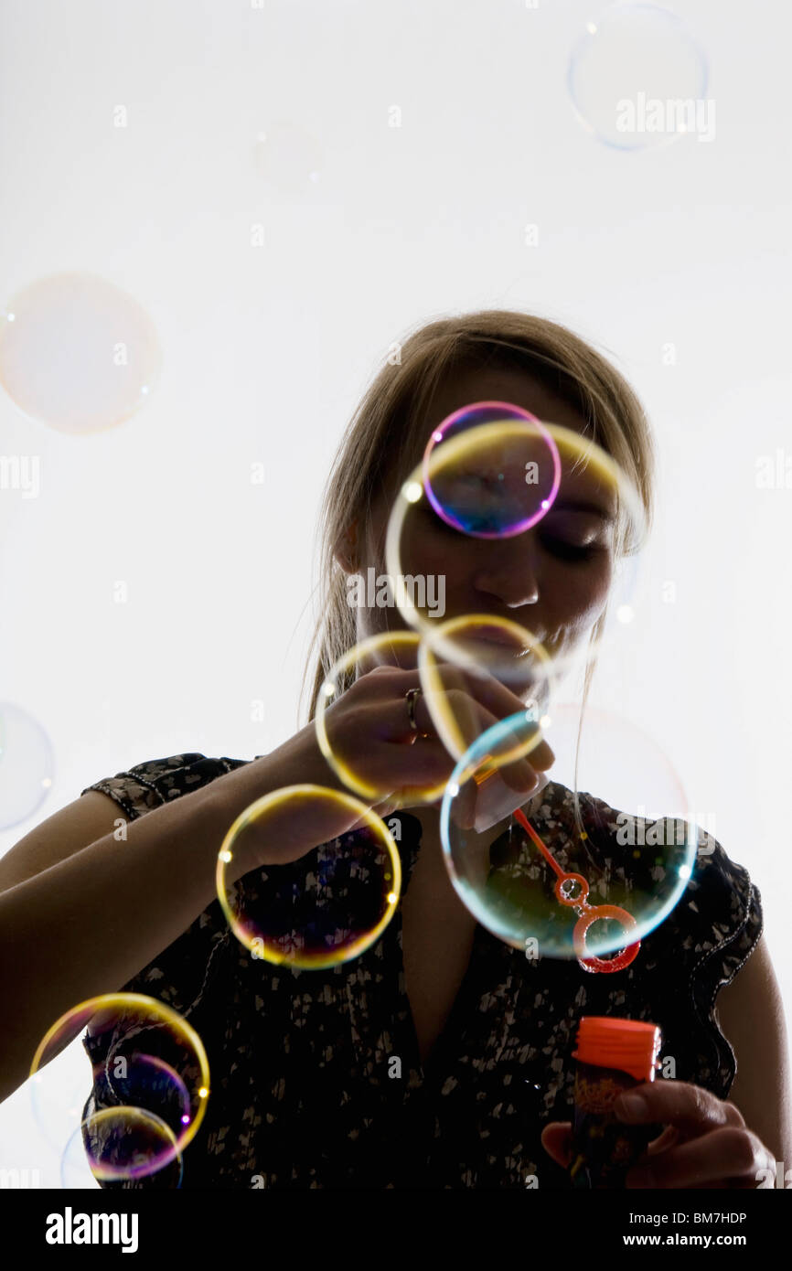 Una mujer soplando burbujas con una varita de burbujas Foto de stock