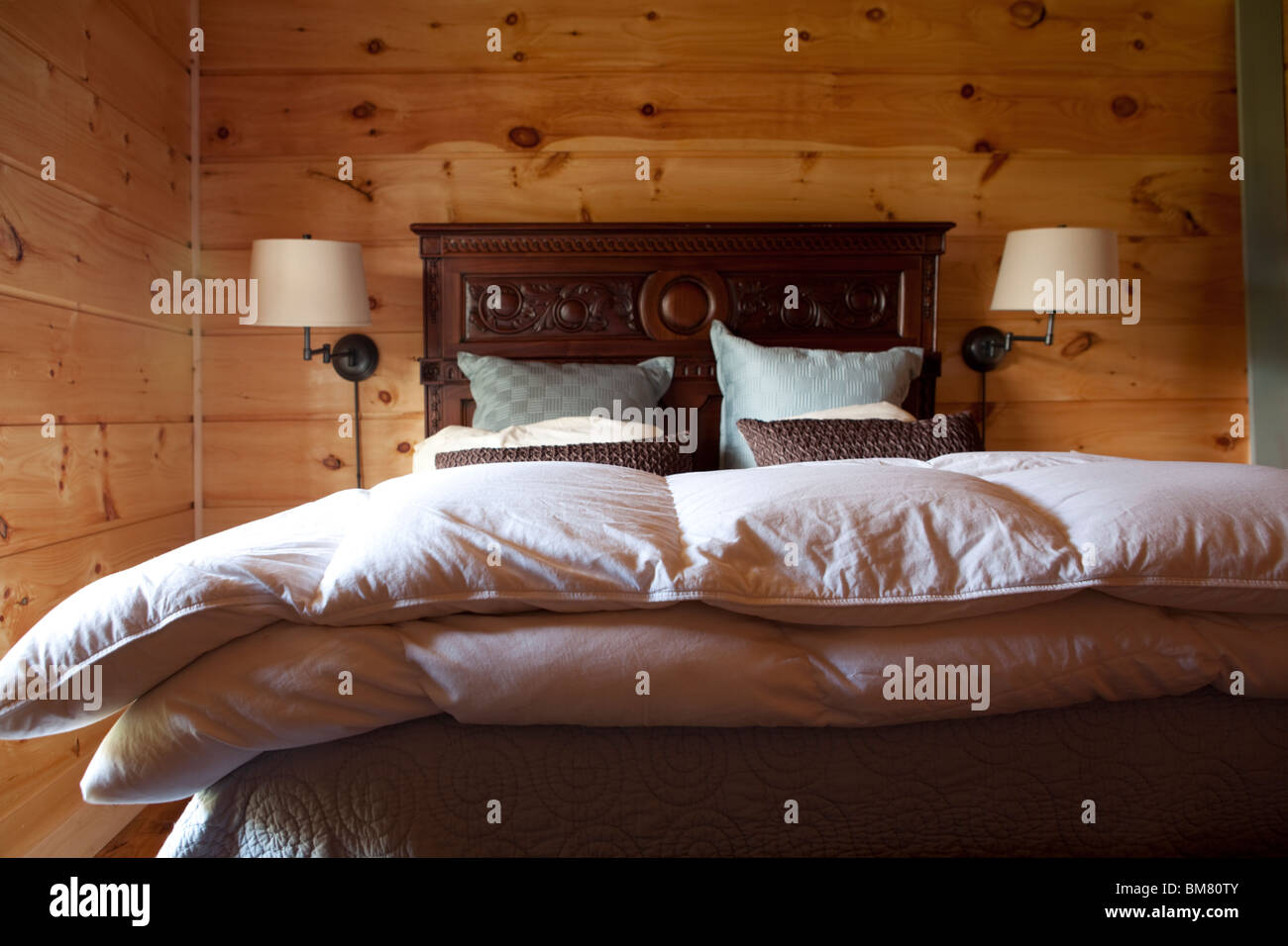 Cabaña de madera dormitorio con cama cama doble edredón y almohadas. Paisaje americano. Ee.Uu. Foto de stock