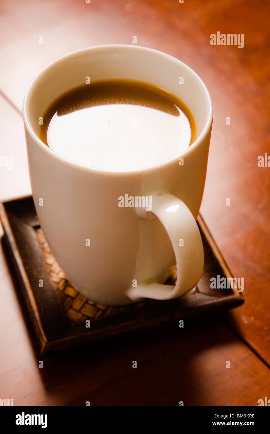 En una taza de café en la mesa marrón luz cálida Foto de stock