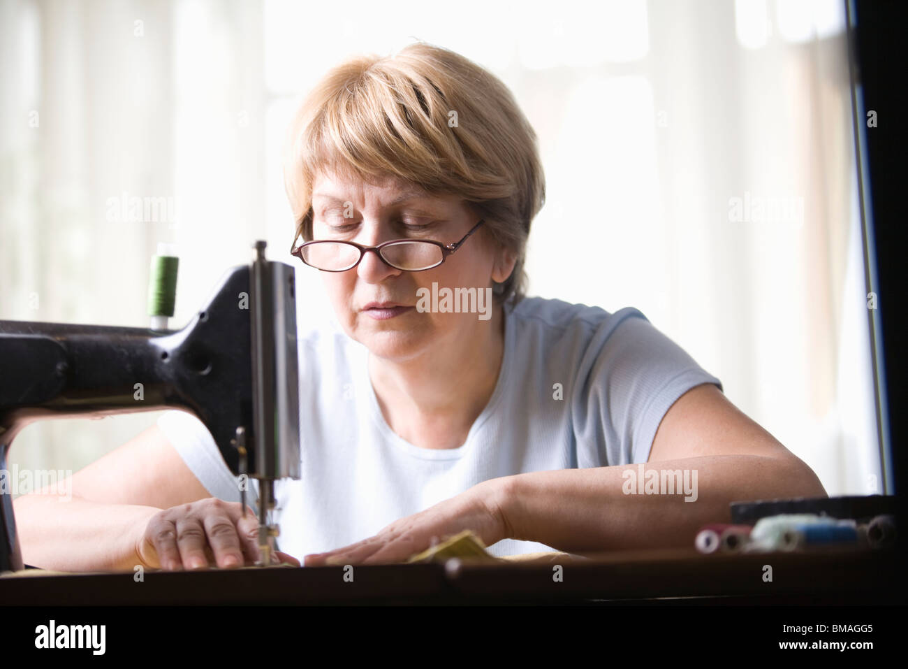 Mujer madura trabaja a máquina de coser Foto de stock