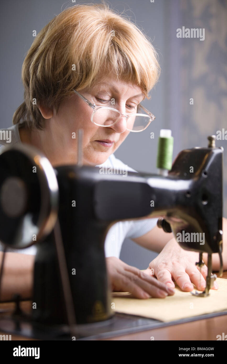 Mujer madura trabaja a máquina de coser Foto de stock